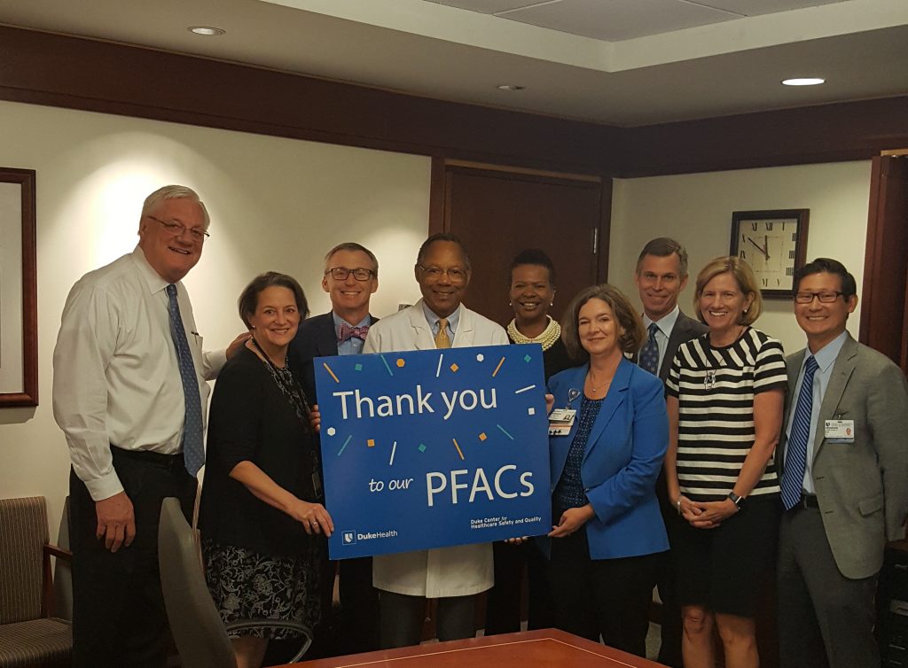 Duke Health senior leaders pose with a "Thank You to our Patient and Family Advisory Councils" poster